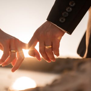 Romantic,Couple,Holding,Hands,Fingers,At,Sunset,Leaking,Wedding,Rings